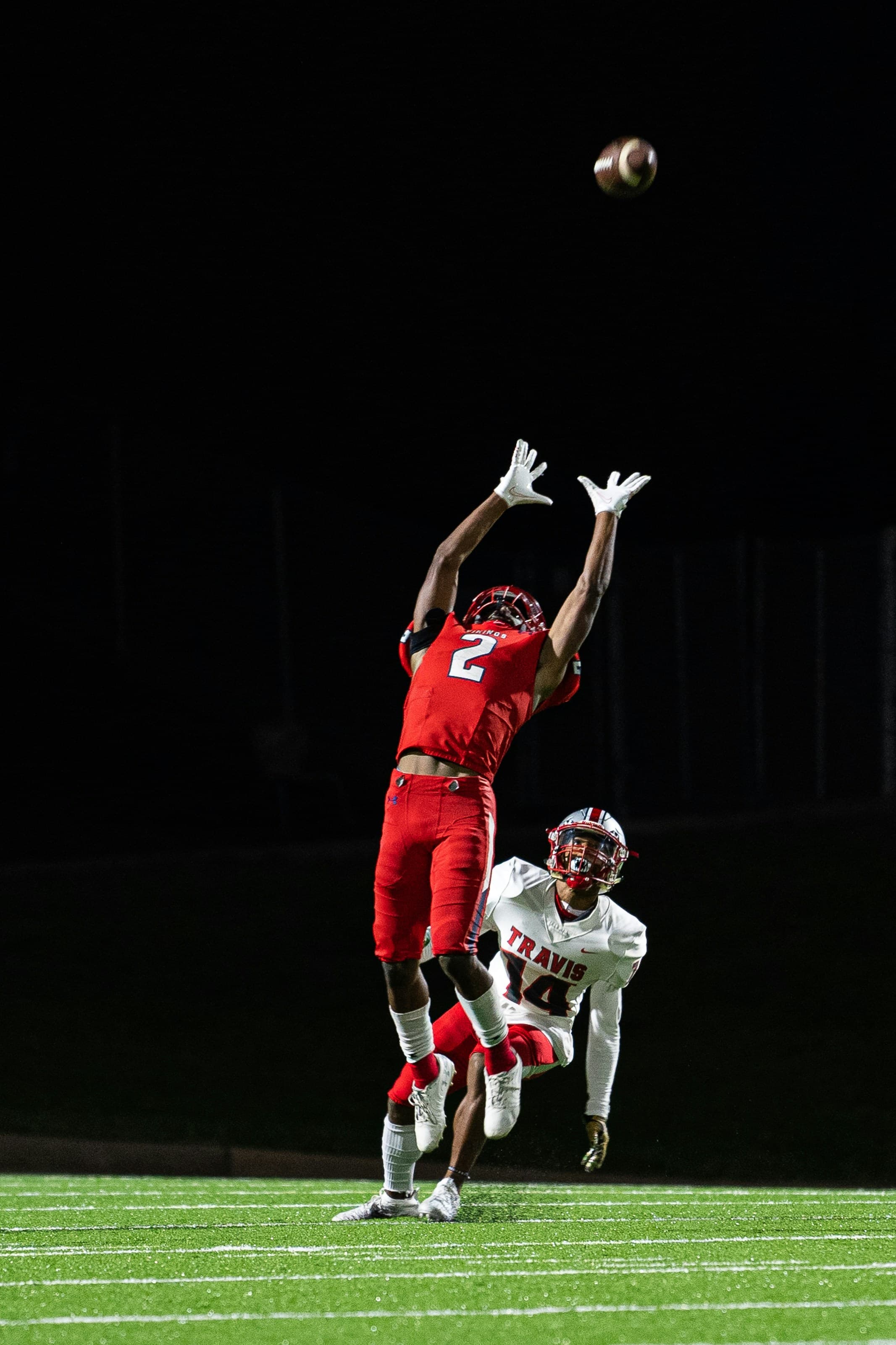 Football player mid-play under stadium lights.